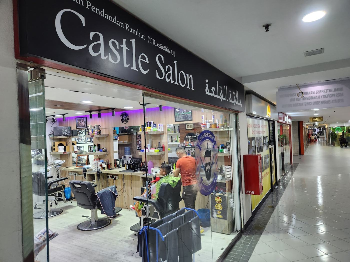 Shopfront with Arabic signboard and barber pole
